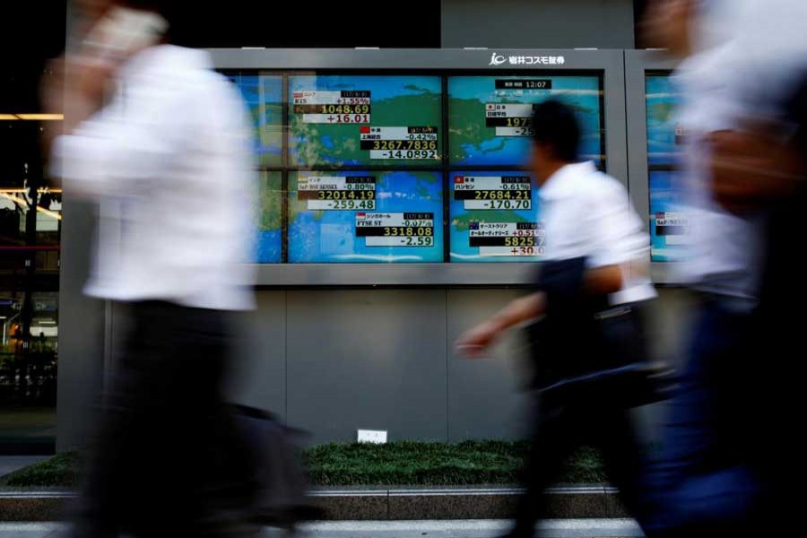 People walk past an electronic board showing Japan's Nikkei average outside a brokerage at a business district in Tokyo, Japan, August 9, 2017. Reuters/Files