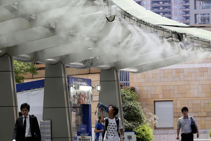 People cool down under the cooling mist spot in Tokyo as temperature rises into record high — AP photo