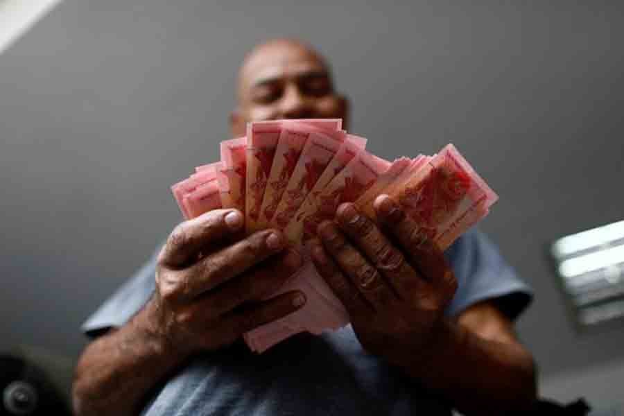 A worker counts Venezuelan bolivar notes at a parking lot in Caracas, Venezuela on May 29. Reuters/File photo