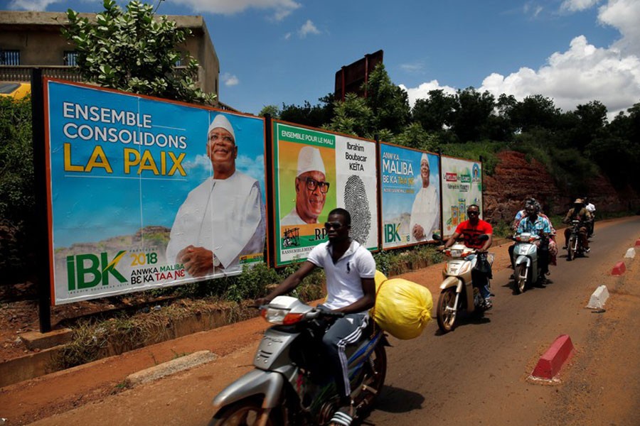 People ride their motorcycle past electoral billboards of Ibrahim Boubacar Keita, the Malian president and leader of RPM (Rassemblement Pour le Mali) in Bamako, Mali on July 23 - Reuters