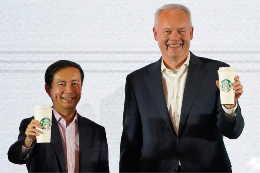 Starbucks CEO Kevin Johnson (R) and Chief Executive Officer of Alibaba Group Holding Ltd. Daniel Zhang hold cups of Starbucks for a picture at a strategic partnership press conference in Shanghai, China on Thursday — Reuters