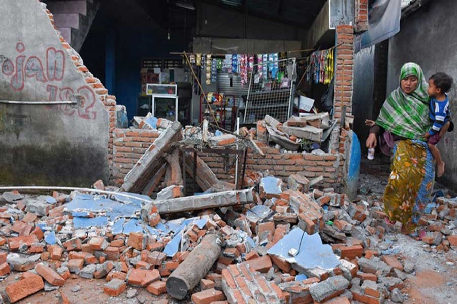 A woman walks past debris from a collapsed wall following a strong earthquake in Lendang Bajur Hamlet, Lombok island, indonesia Aug 6, 2018 in this photo taken by Antara Foto. Reuters