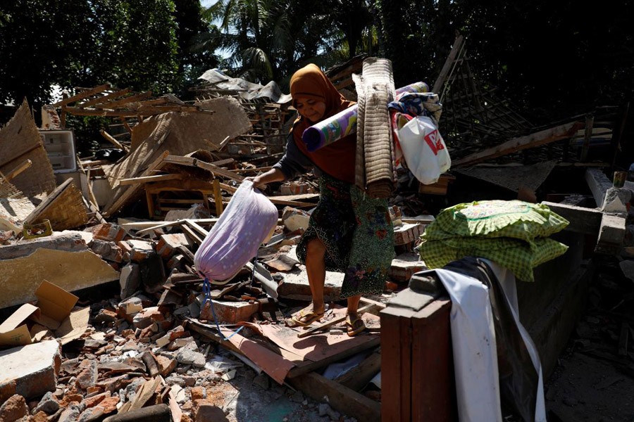 A woman carries valuable goods from the ruins of her house at Kayangan district after earthquake hit on Sunday in North Lombok, Indonesia, August 7, 2018 – Reuters