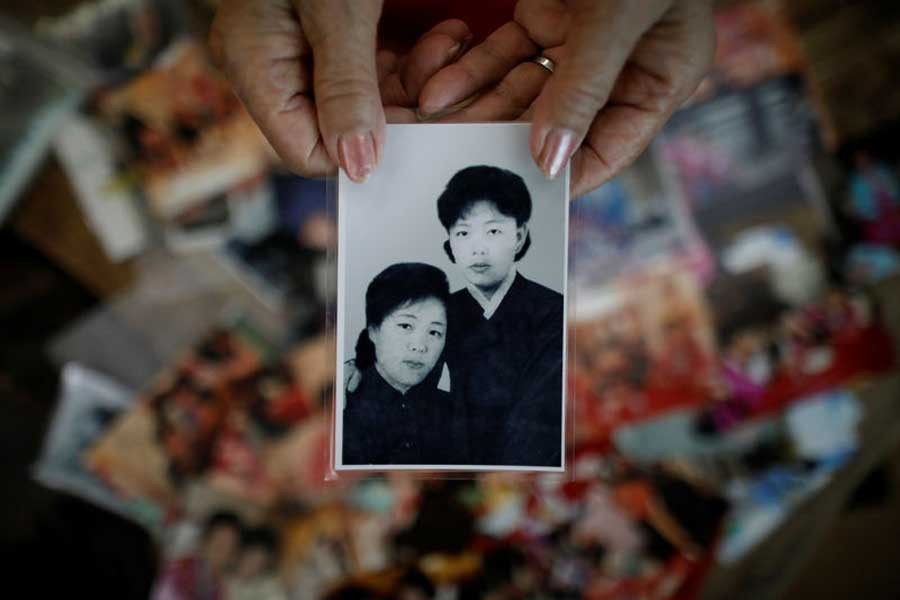 Kim Hyun-sook poses for photographs with an old photo showing her daughters, during an interview with Reuters at her home in Seoul, South Korea, August 2, 2018. Reuters/File Photo