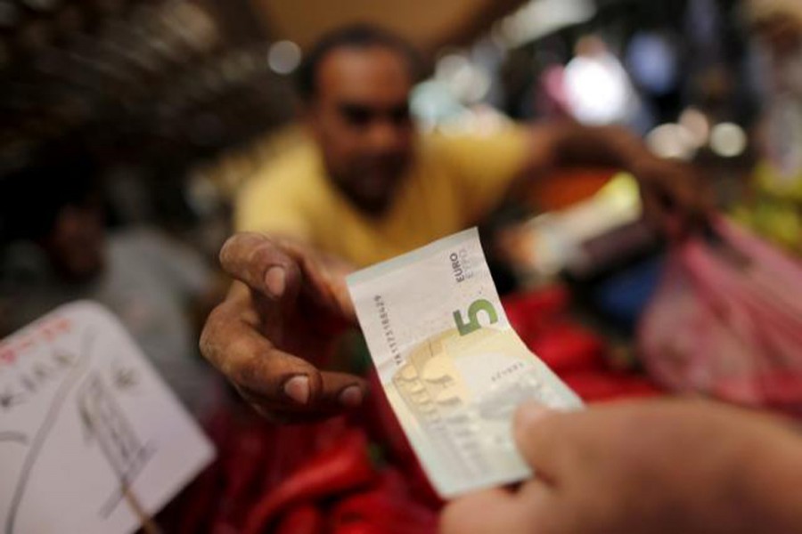 A vendor receiving a five-Euro bank note from a customer at the central market in Athens, Greece	— Reuters