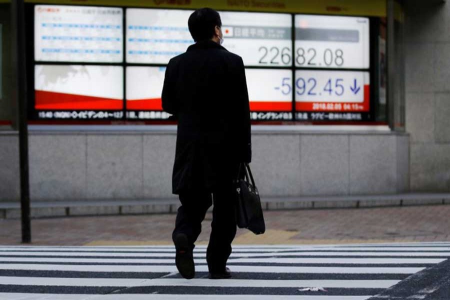 A man walks past an electronic board showing Japan's Nikkei average outside a brokerage in Tokyo, Japan February 5, 2018. Reuters/FIle Photo