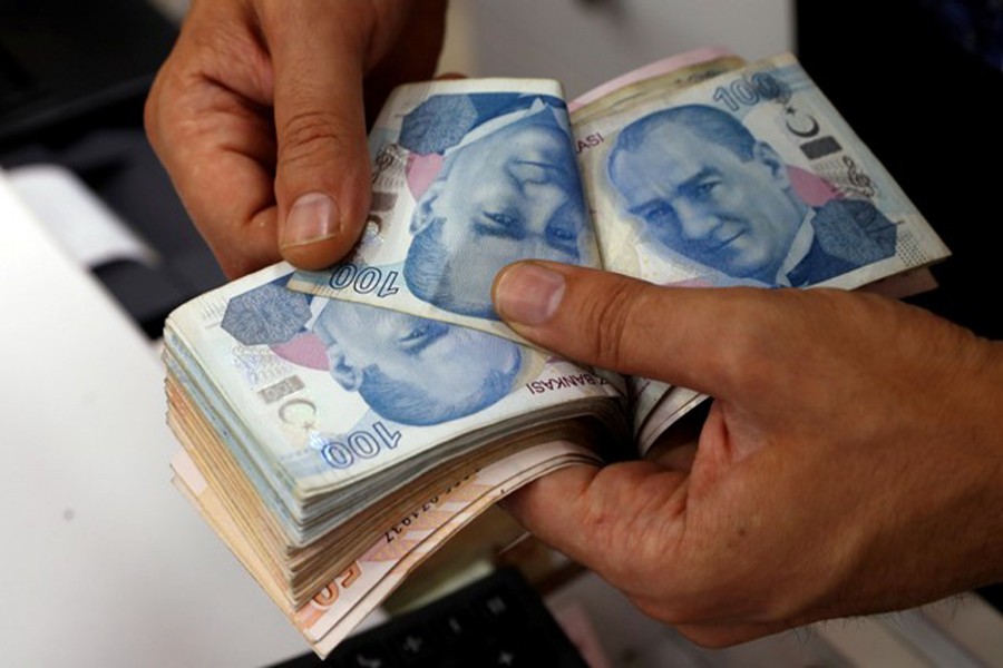 A money changer counting Turkish lira banknotes at a currency exchange office in Istanbul, Turkey   	— Reuters