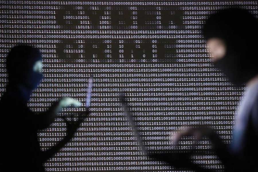 Representational image: People wearing balaclavas are silhouetted as they pose with a laptops in front of a screen projected with the word 'cyber crime' and binary code, in this picture illustration taken in Zenica October 29, 2014. Reuters/Files