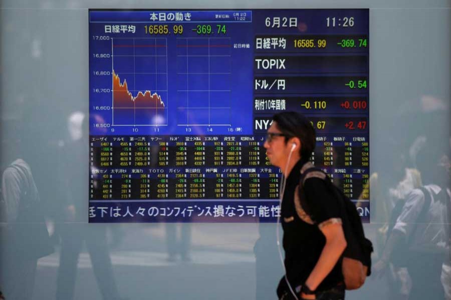 A man walks in front of a screen showing today's movements of Nikkei share average outside a brokerage in Tokyo, Japan, June 2, 2016. Reuters/File Photo