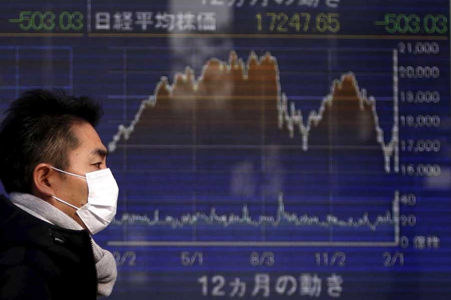 A pedestrian walks past an electronic board showing the graph of the recent fluctuations of Japan's Nikkei average outside a brokerage in Tokyo, Japan, February 3, 2016. Reuters/File Photo