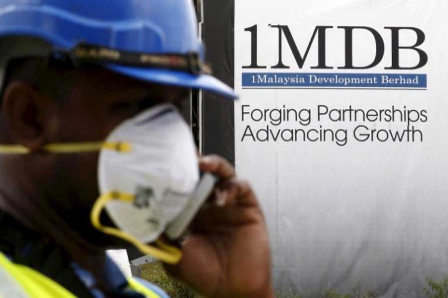 A construction worker talks on the phone in front of a 1Malaysia Development Berhad (1MDB) billboard at the Tun Razak Exchange development in Kuala Lumpur, Malaysia, February 3, 2016. Reuters/File Photo