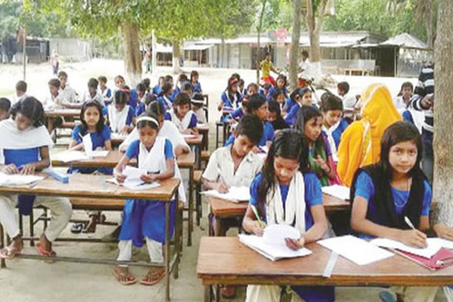 Students of Government Primary School in Manairi union under Atrai upazila of Naogaon sitting for a examination under the open sky  	— FE Photo