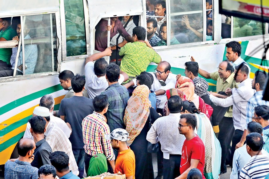 Passengers' frantic efforts to get into a bus in Paltan area in the city on Monday. The city is experiencing a shortage of transports after the launch of the traffic campaign — FE photo