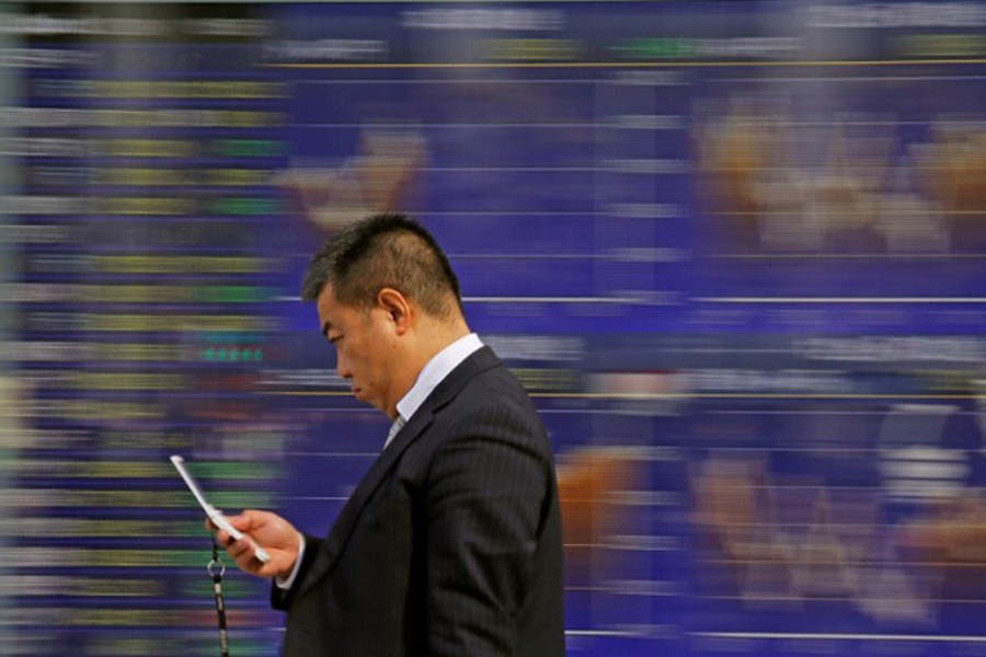 A man walks past an electronic stock quotation board outside a brokerage in Tokyo, Japan, February 9, 2018. Reuters/Files