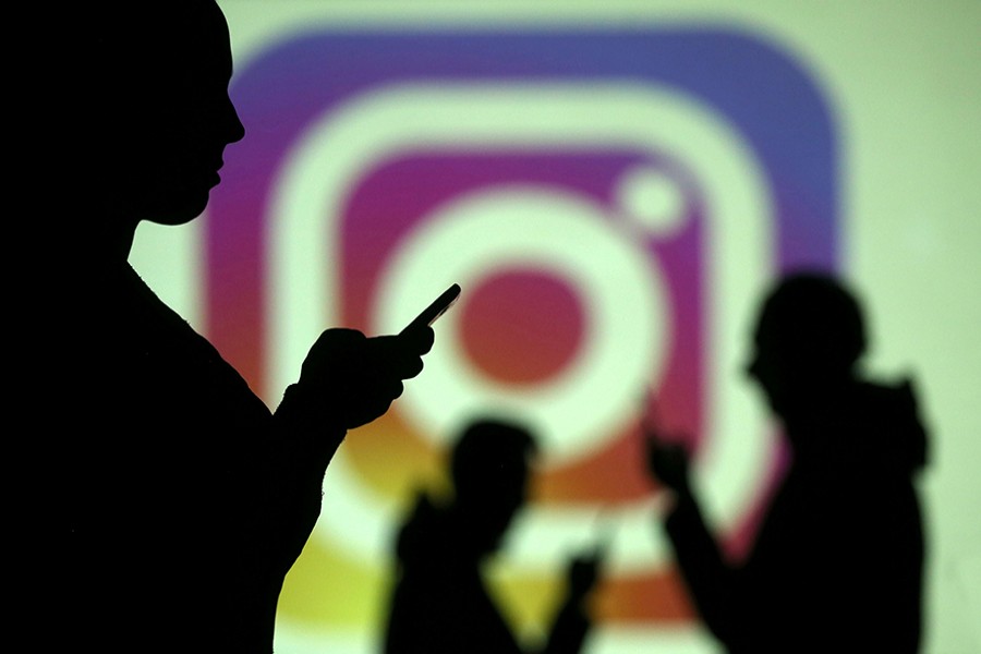 Silhouettes of mobile users are seen next to a screen projection of Instagram logo in this picture illustration taken on March 28 last — Reuters/File