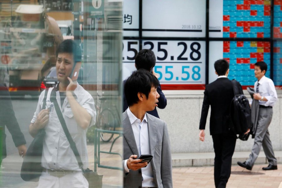 People walk past an electronic board showing Japan's Nikkei average outside a brokerage in Tokyo, Japan, October 12, 2018. Reuters