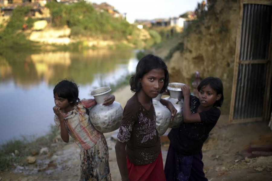 Rohingya Muslim girls carry water pots in Kutupalong refugee camp in Bangladesh, November 19, 2017. Associated Press/Files