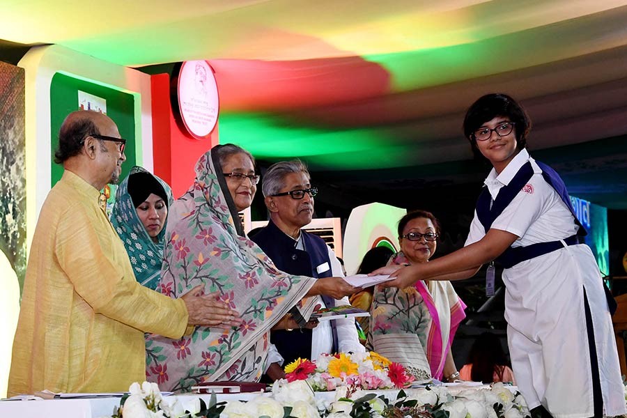 Prime Minister Sheikh Hasina on Friday handing over prize to a winner of drawing and essay writing competitions organised on the occasion of Bangabandhu's birthday. -Focus Bangla Photo