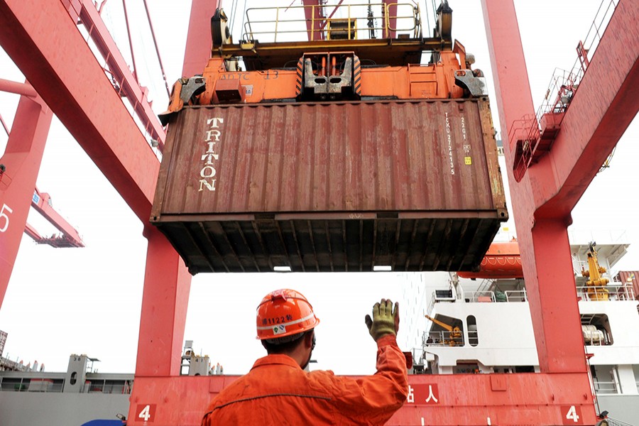 An employee guides a crane as it unloads shipping containers from a cargo ship at a port in Lianyungang, Jiangsu province on March 8, 2014 — Reuters/File