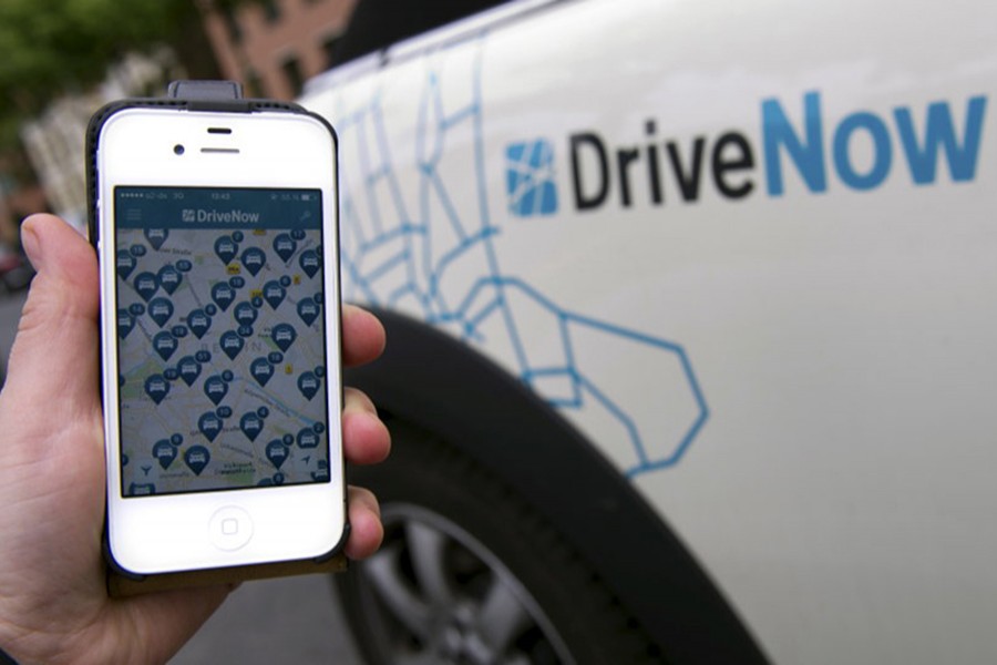 A smartphone displaying the DriveNow app with cars available in Berlin's city centre is held up next to a car from the DriveNow service in this picture illustration taken in Berlin, Germany on May 27, 2015 — Reuters/File