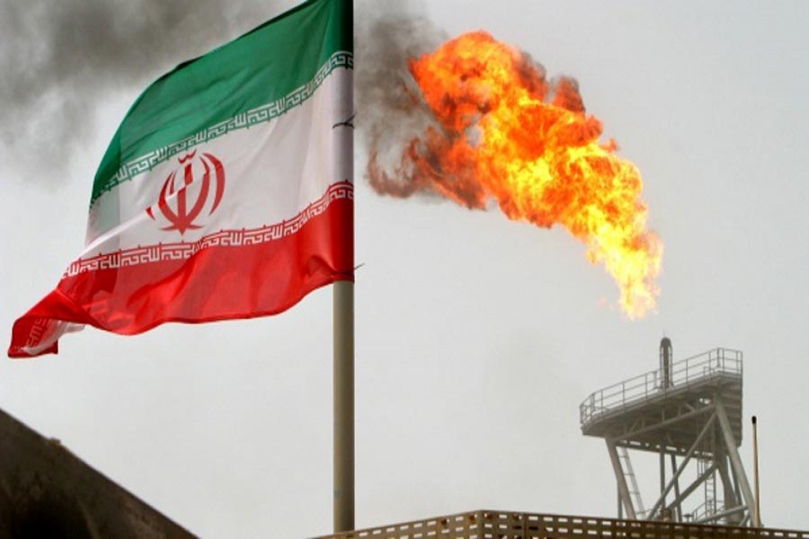 A gas flare on an oil production platform in the Soroush oil fields is seen alongside an Iranian flag in the Persian Gulf, Iran       	— Reuters