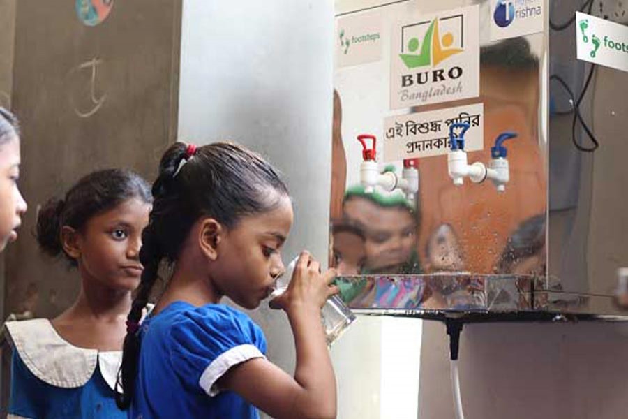 A school girl drinking from the safe drinking water system implemented by Footsteps Foundation in association with Buro Bangladesh