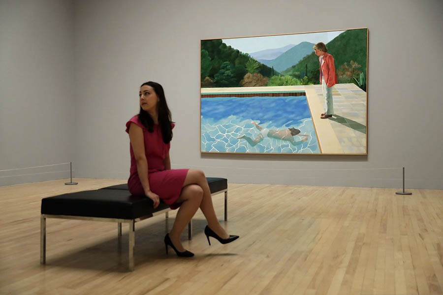 A Tate representative sits next to British artist David Hockney's "Portrait of an Artist (Pool with Two Figures) during a photo call to promote the largest-ever retrospective of his work at Tate Britain gallery in London. Photo: Collected