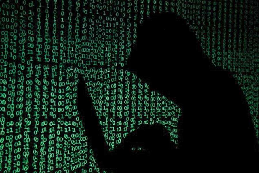 A hooded man holds a laptop computer as cyber code is projected on him in this illustration picture taken on May 13, 2017.        — Photo: Reuters