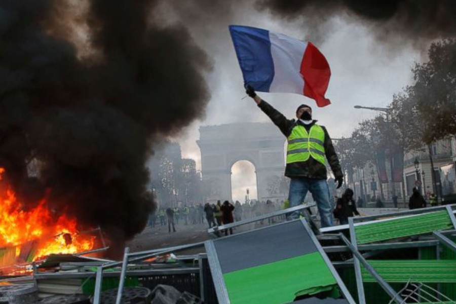A demonstrator waves the French flag on the Champs-Elysees during a protest against the rising of the fuel taxes, Nov 24, 2018 in Paris - AP
