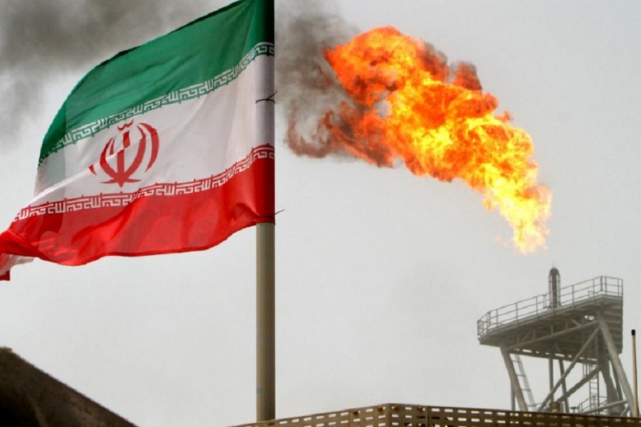 In this Reuters file photo, a gas flare on an oil production platform in the Soroush oil fields is seen alongside an Iranian flag in the Persian Gulf, Iran.