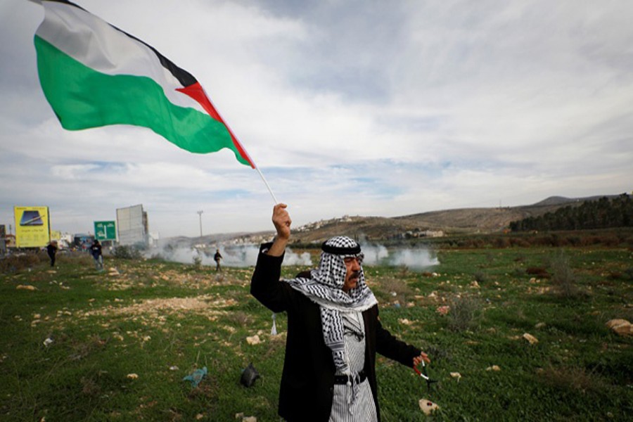 A demonstrator holds a Palestinian flag during clashes with Israeli troops at the Hawara checkpoint near Nablus in the occupied West Bank, December 2, 2018. Reuters/Files