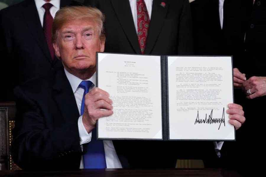 US President Donald Trump holds his signed memorandum on intellectual property tariffs on high-tech goods from China, at the White House in Washington on March 22, 2018. -Reuters