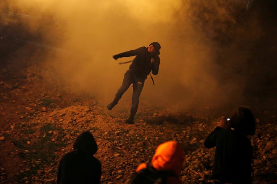 A migrant, part of a caravan of thousands from Central America trying to reach the United States, throws back a tear gas bomb after US Customs and Border Protection (CBP) throw tear gas to the Mexican side of the fence as they prepared to cross it illegally, in Tijuana, Mexico, January 1, 2019 - REUTERS/Mohammed Salem