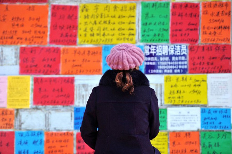 A woman looks at job advertisements on a wall in Qingdao West Coast New Zone in Shandong province, China, January 17, 2019. Reuters