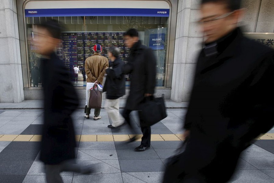 A pedestrian looks at various stock prices outside a brokerage in Tokyo, Japan, February 26, 2016. Reuters/Files