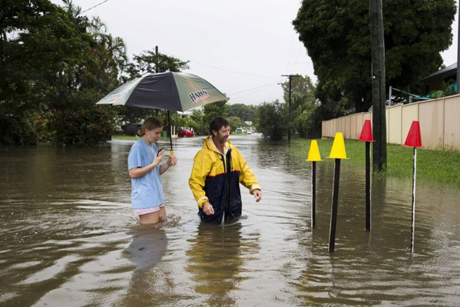 Resident Paul Shafer and his daughter Lily stand in floodwaters near star pickets that show where the storm water cover has been removed in Hermit Park, Townsville, in northern Queensland, Australia, on Feb 2, 2019 - REUTERS