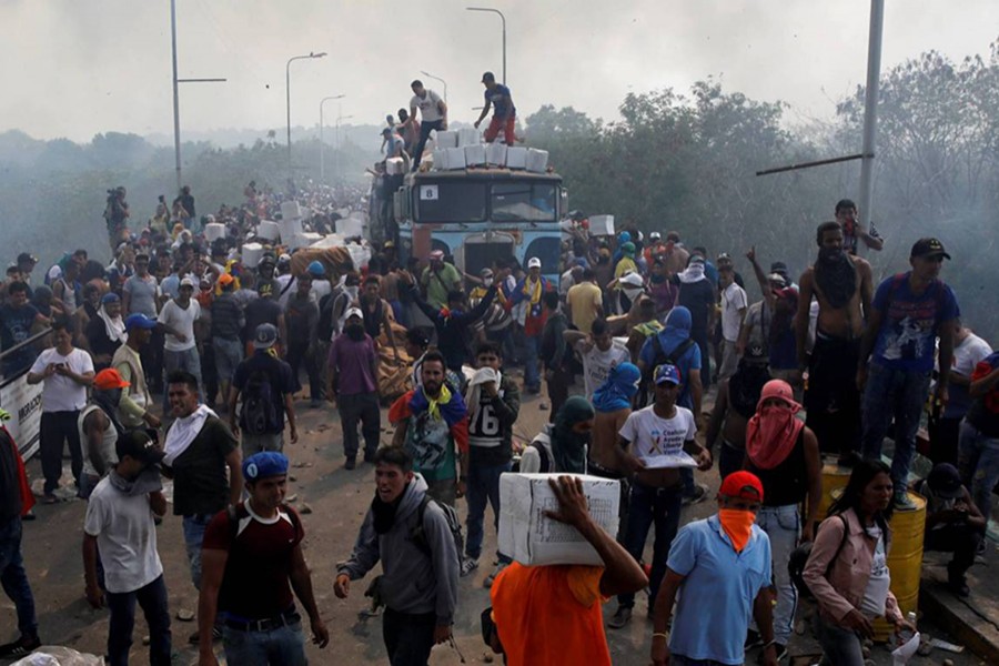 Opposition supporters unload humanitarian aid from a truck that was set on fire after clashes between opposition supporters and Venezuela's security forces at Francisco de Paula Santander bridge on the border line between Colombia and Venezuela as seen from Cucuta, Colombia on Saturday — Reuters photo