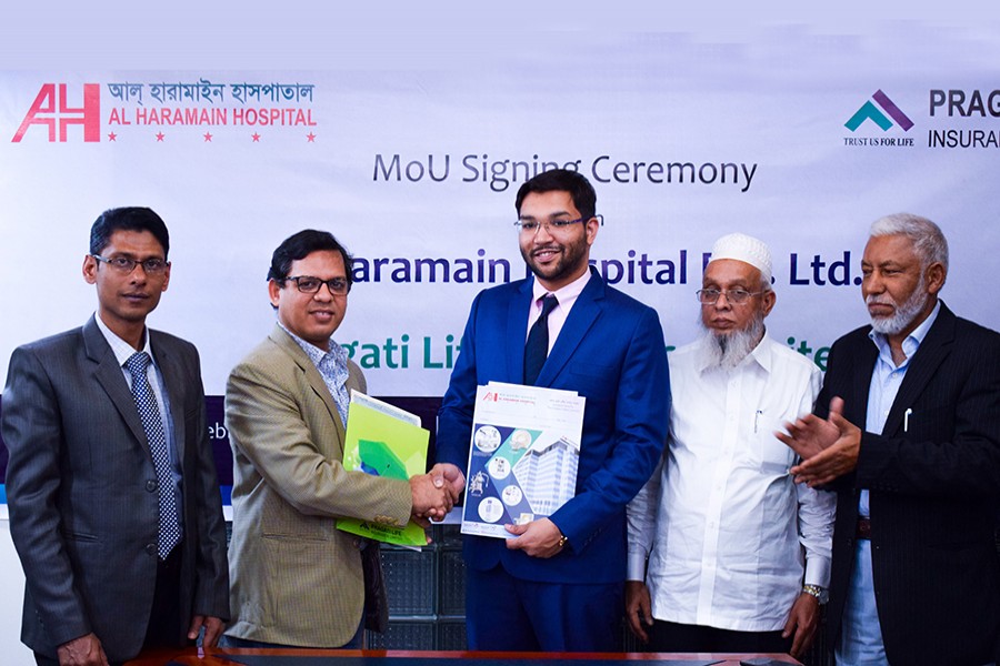 S M Ziaul Hoque, General Manager of Pragati Life Insurance (second from left) and Dr Mohammed Ehsanur Rahman, Managing Director of Al Haramain Hospital Pvt Ltd (third from right) seen exchanging documents on behalf of their respective organisations