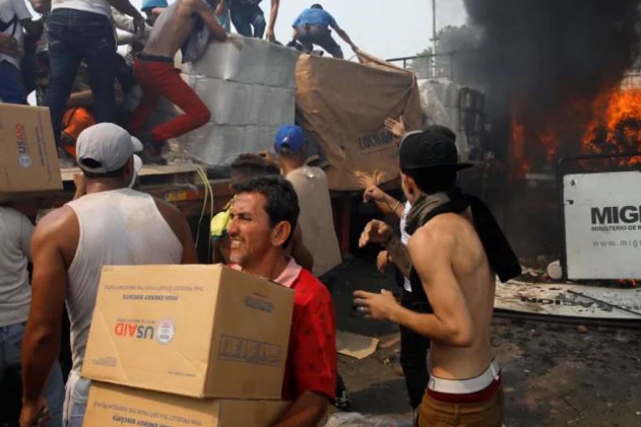 Venezuela's opposition supporters unload humanitarian aid from a truck that was sent on fire after clashes with security forces at the Colombia-Venezuela border, Feb 23, 2019 - Marco Bello/Reuters