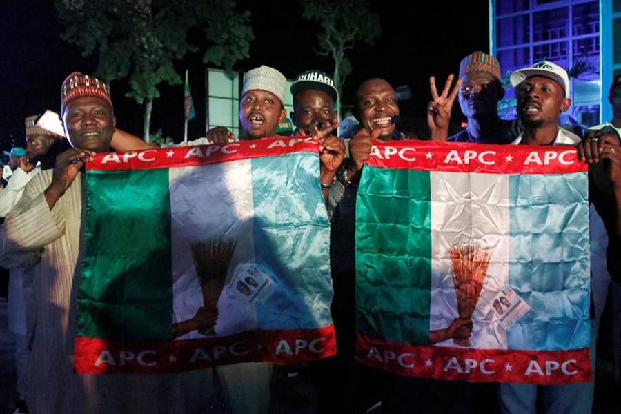 Supporters of Nigeria's President Muhammadu Buhari carry APC flags as they celebrate at the campaign headquarters of All Progressives Congress (APC) in Abuja, Nigeria on Tuesday — Reuters photo