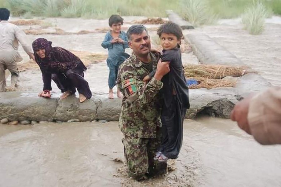 An Afghan soldier carries a child as they conduct rescue operations in flooded areas — Photo via Twitter