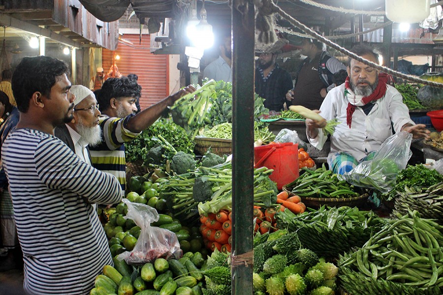 A vegetable vendor at Kaptan Bazar in the capital seen packing an order for one of his customers in this undated Focus Bangla photo