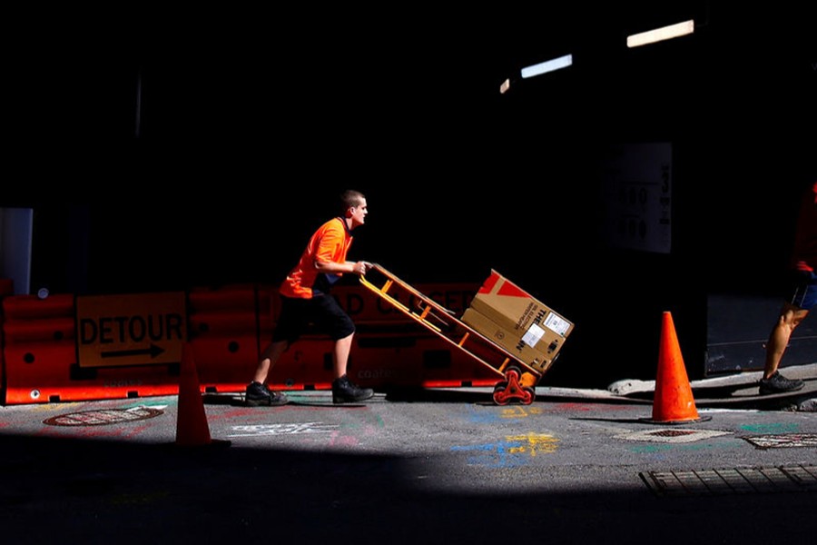 A worker pushes a trolley loaded with goods past a construction site in the central business district (CBD) of Sydney in Australia on March 15, 2018 — Reuters/file