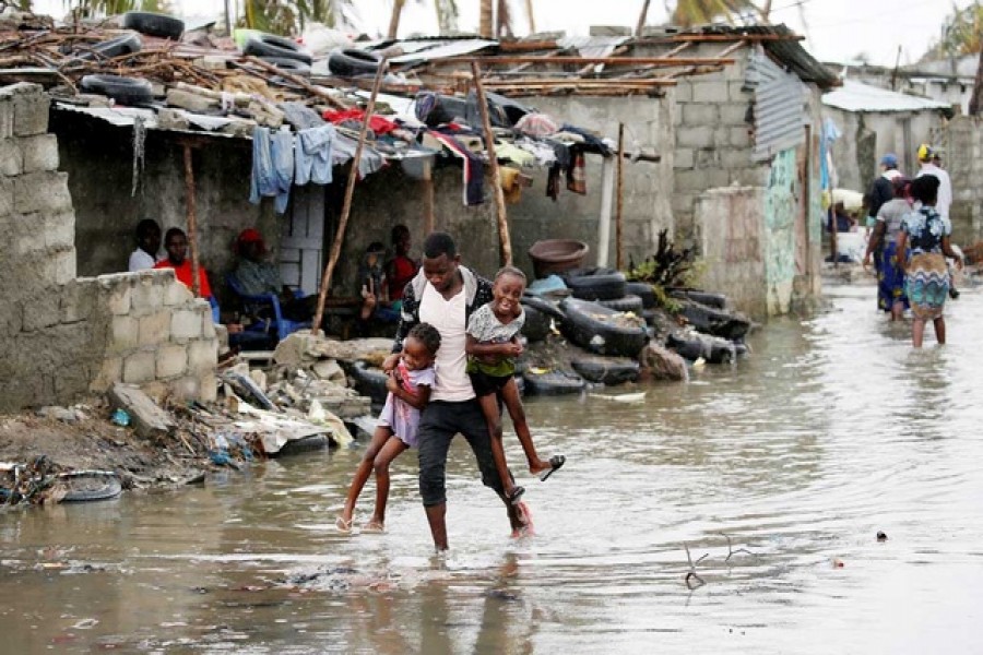 A man carries his children after Cyclone Idai at Praia Nova, in Beira, Mozambique, Mar 23, 2019.  - Reuters