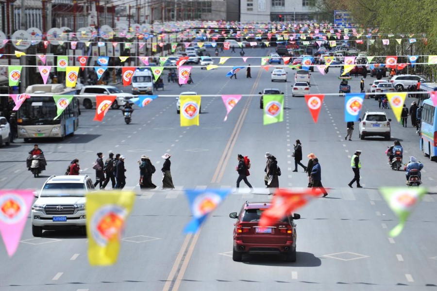 People cross a road under flags marking Tibetan Serfs' Emancipation Day on March 28, in Lhasa, Tibet Autonomous Region, China March 26, 2019. Picture taken March 26, 2019 - REUTERS/Stringer