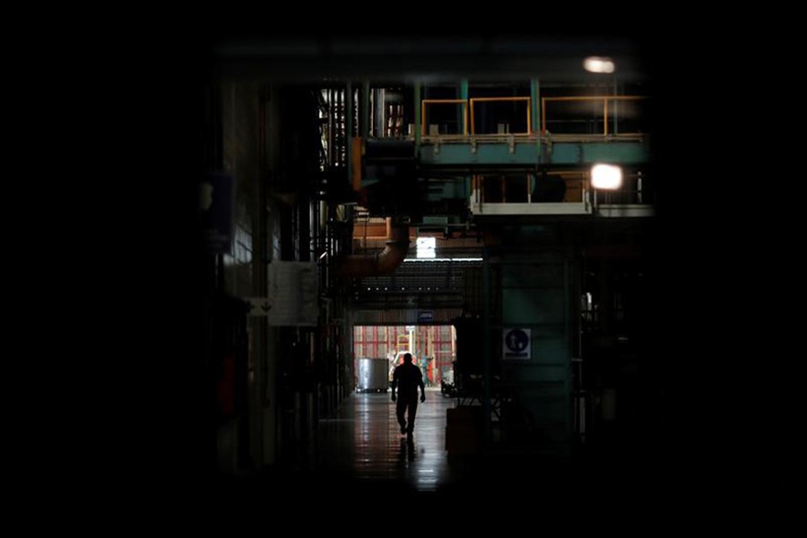 A worker walking next to halted machines at a cans' factory during a power cut in Valencia in Venezuela recently. -Reuters Photo
