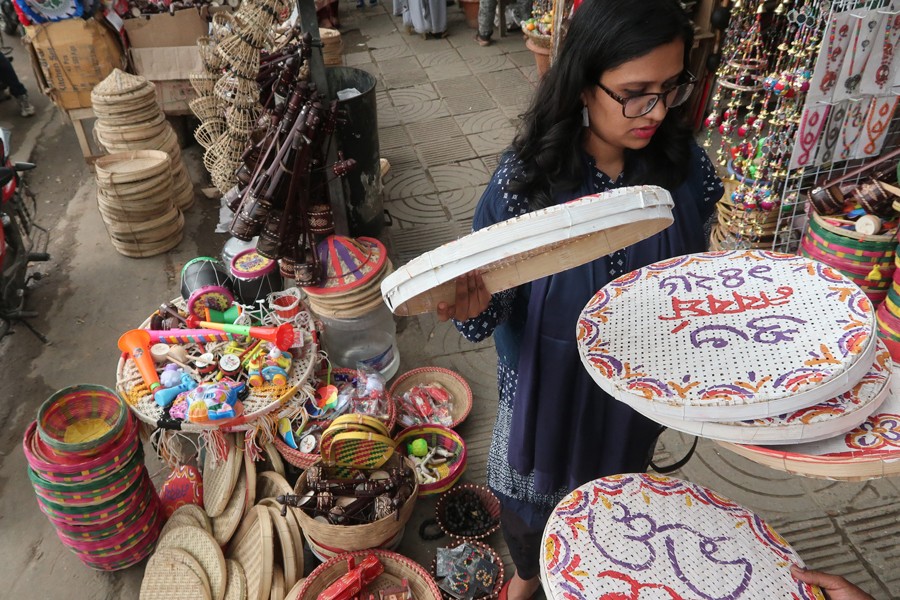 A woman choosing decor items at a shop at Doyel Chattar in Dhaka city ahead of the Pahela Baishakh celebration      	— FE photo