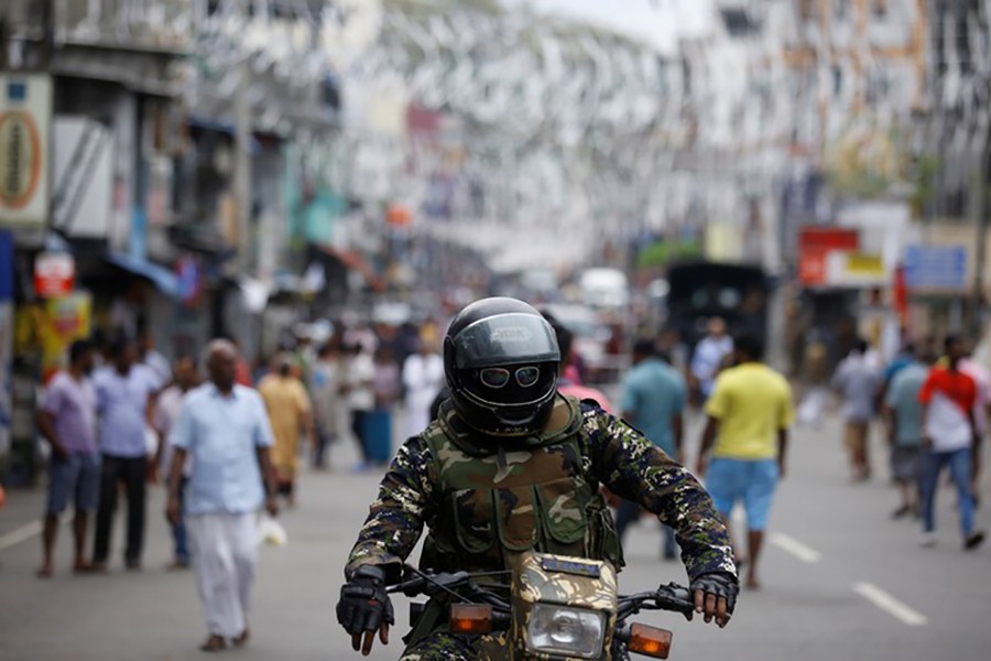 A member of the Sri Lankan security forces sits on a motorbike as he keeps watch outside St Anthony's Shrine, days after a string of suicide — Reuters photo