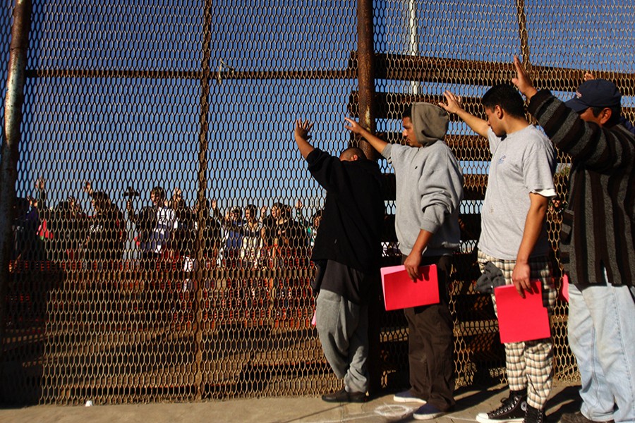 A group of deported immigrants stands near the double steel fence that separates San Diego and Tijuana — Reuters/Files