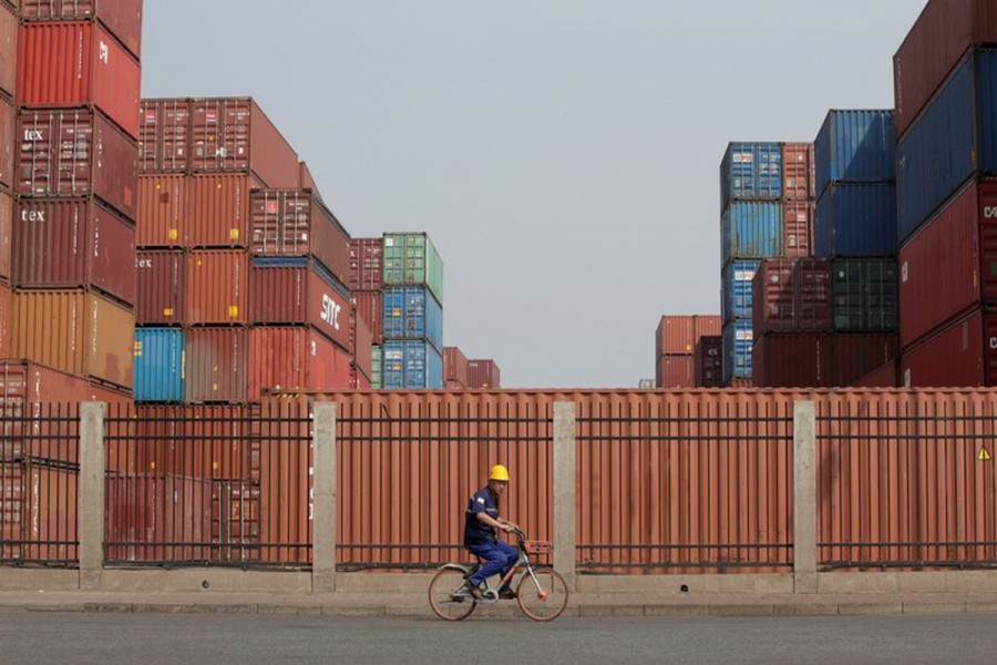 A worker cycles past containers outside a logistics centre near Tianjin Port, in northern China, May 16, 2019. Reuters